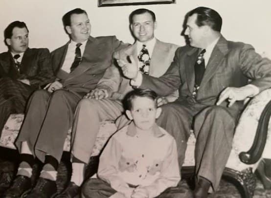 Vintage black-and-white photo of the Cox brothers and a cousin seated together, with Joe as a boy in front