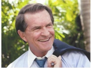 Portrait of Joseph B. Cox in his middle years, dark hair, white dress shirt, suit jacket held over one shoulder, Naples palm-tree backdrop