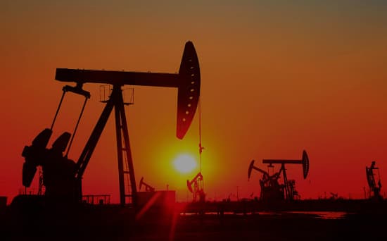 Oil derricks silhouetted against a sunset on the Oklahoma plains